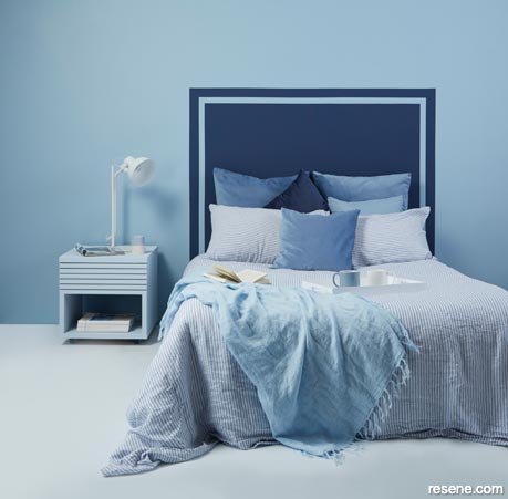 A light blue master bedroom with a dark blue headboard