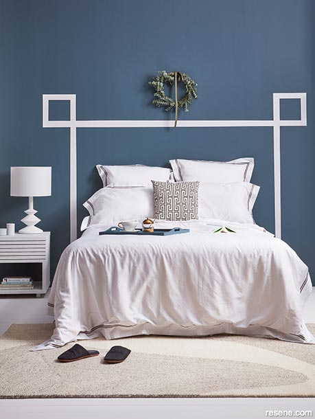 A regal blue bedroom with a headboard made of simple classic lines