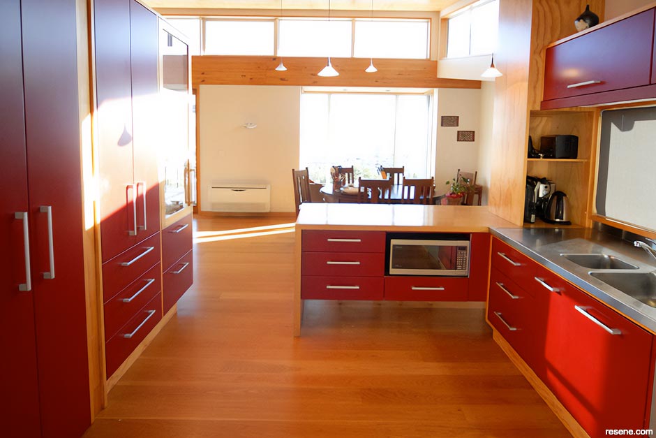 A bold red kitchen with stained timber floors