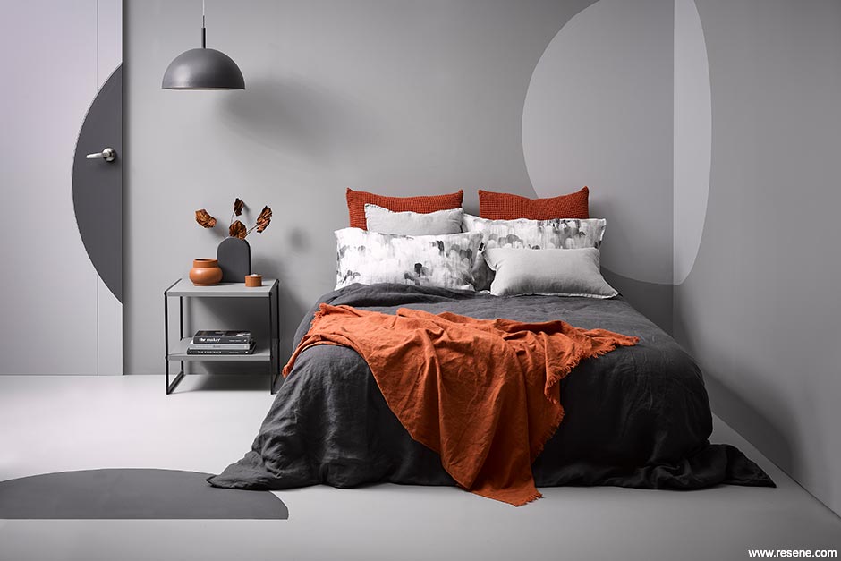 A greyscale bedroom with brown/orange accessories