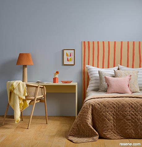 Grey bedroom with painted orange striped headboard