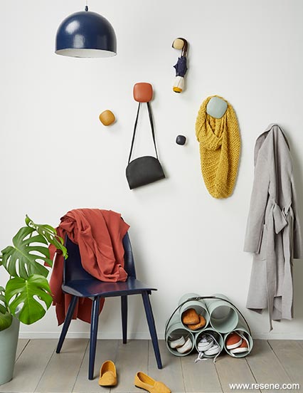 A neutral entryway with colourful chairs, hooks and accessories