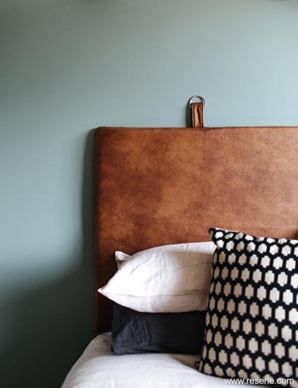 Pale green wall with contrasting leather headboard