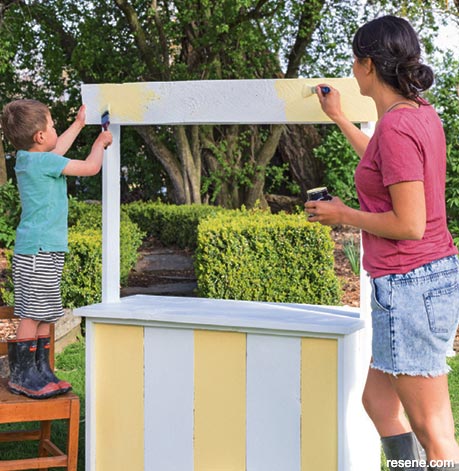 Nadia painting a roadside stand with her kids